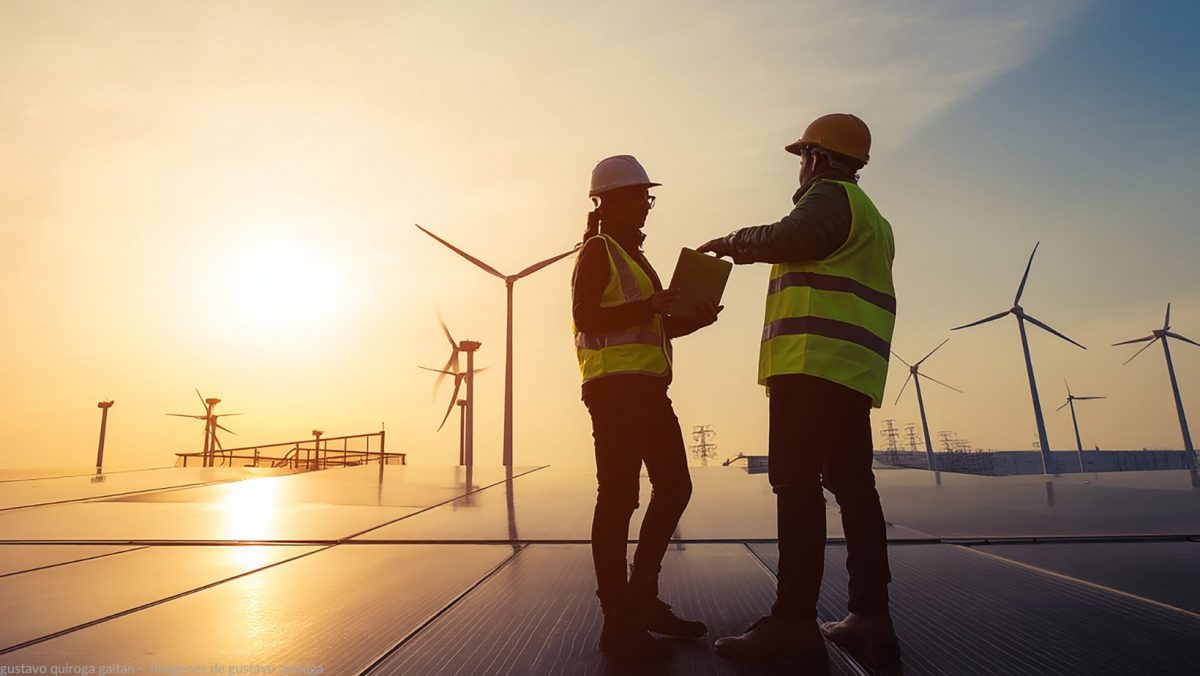 Auf dem Bild sind zwei Personen zu sehen. Im Hintergrund sind Windräder und solaranalogen zu sehen.