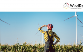 Auf dem Bild ist eine Frau zu sehen, die in die Ferne auf Windräder Blickt.