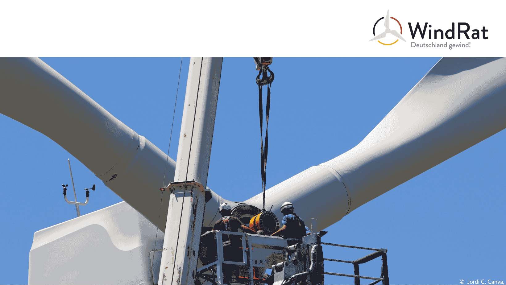 Menschen mit einem Kran auf Höhe eines Windrads bei Bauarbeiten, die Repowering symbolisieren.