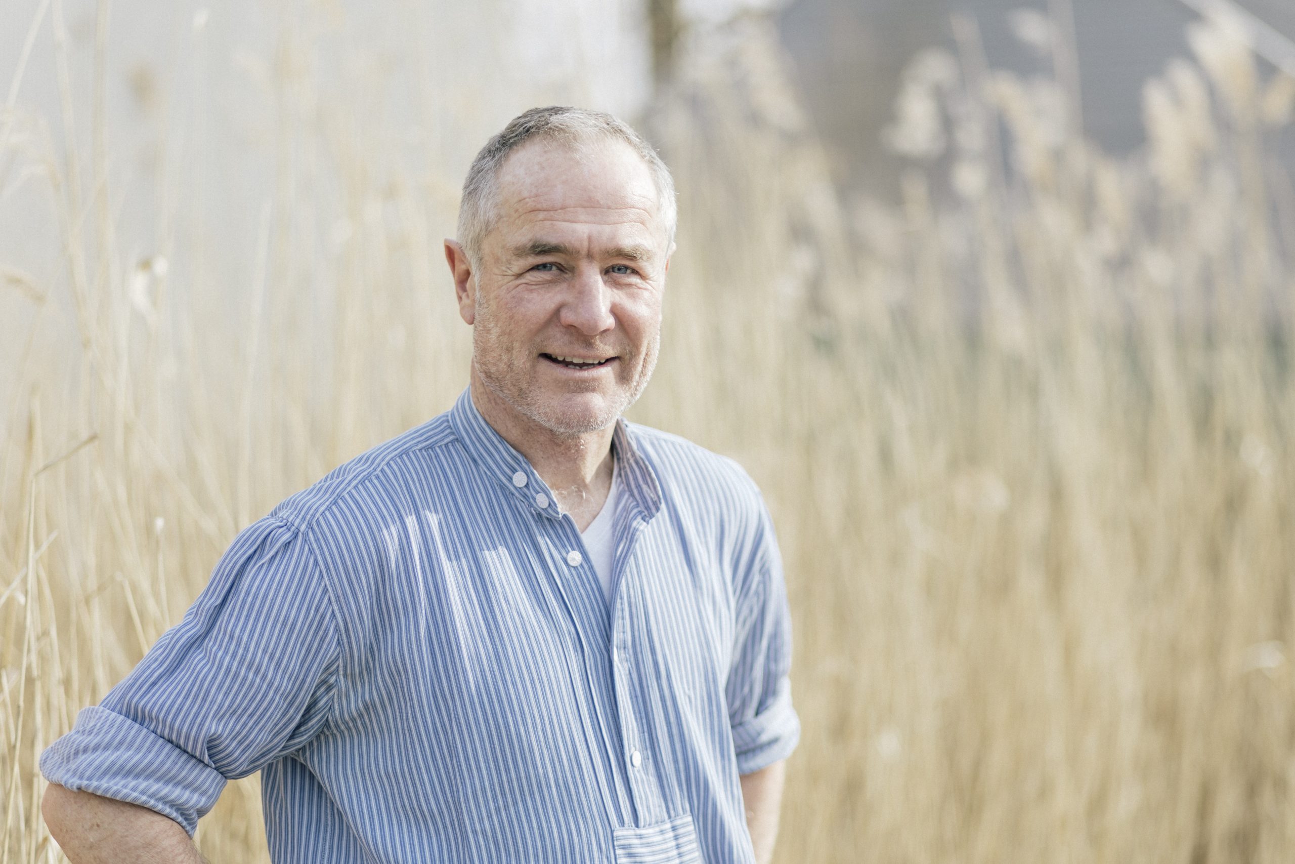 Porträtfoto von WindRat-Projektmanager Peter Keller, Nahaufnahme mit hellblauem Hemd in einem Feld.