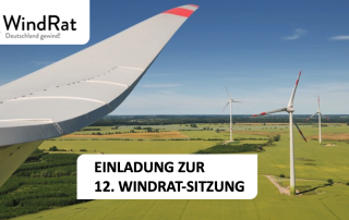 Man sieht einen Windpark auf grüner Wiese vor blauem Himmel. Ganz nah einen Flügel eines der Windräder. Im oberen Eck sieht man das Logo des WindRats, Text auf dem Bild: "Einladung zur 12. WindRat-Sitzung"
