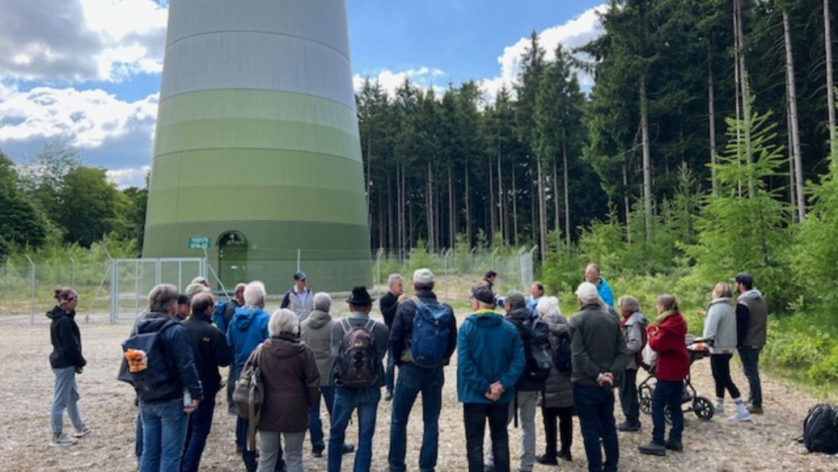 Teilnehmer*innen der Exkursion stehen vor einem Windrad