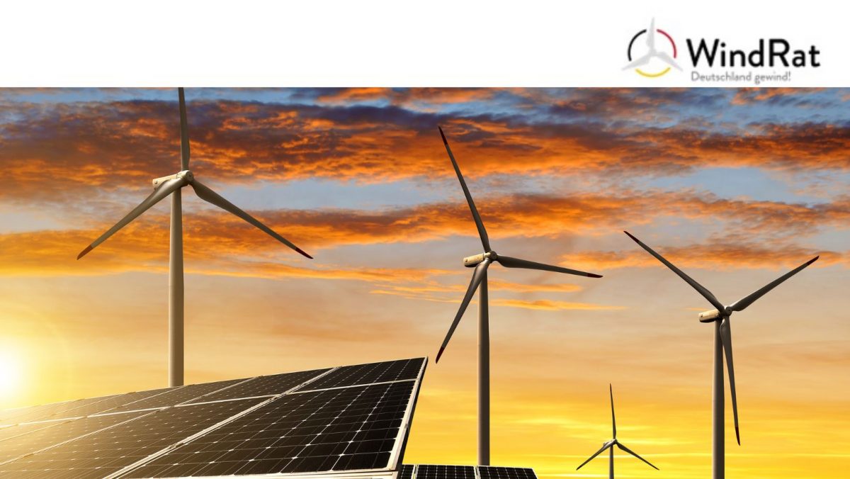 Auf dem Bild sind Windräder und Solaranlagen im Sonnenuntergang zu sehen.