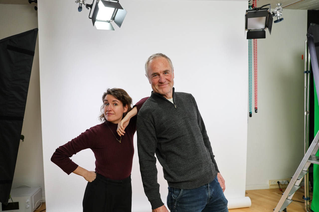 Die beiden Hosts des Windkanals für Fakten zu Windenergie, Fenya Kirst und Peter Keller, vor einer weißen Leinwand in einem Fotostudio.